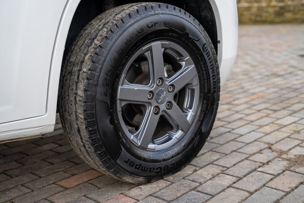 A close-up view of a gray alloy wheel fitted with a Continental tire on the 2017 Swift Escape 664, parked on a brick-paved surface.