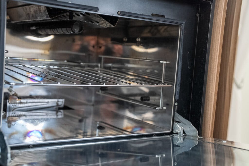 Close-up of the interior of a clean, stainless steel oven with an open door in the 2017 Swift Escape 664. The image showcases the oven racks and reflective metal surfaces inside, highlighting its pristine condition.