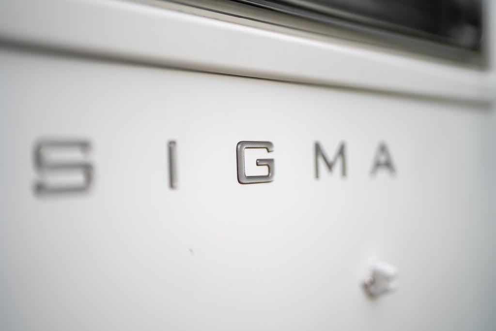 Close-up of a white surface with the word "SIGMA" in metallic letters attached to it, reminiscent of the 2007 Auto-Sleepers Sigma EL. The letters are evenly spaced, and the background appears slightly out of focus.