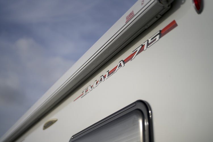 A close-up shot of a white 2014 Auto-Trail Imala 715 Lowline with the brand name "IMALA 715" displayed on its side in red and silver lettering. The sky is visible in the background, suggesting an outdoor setting.