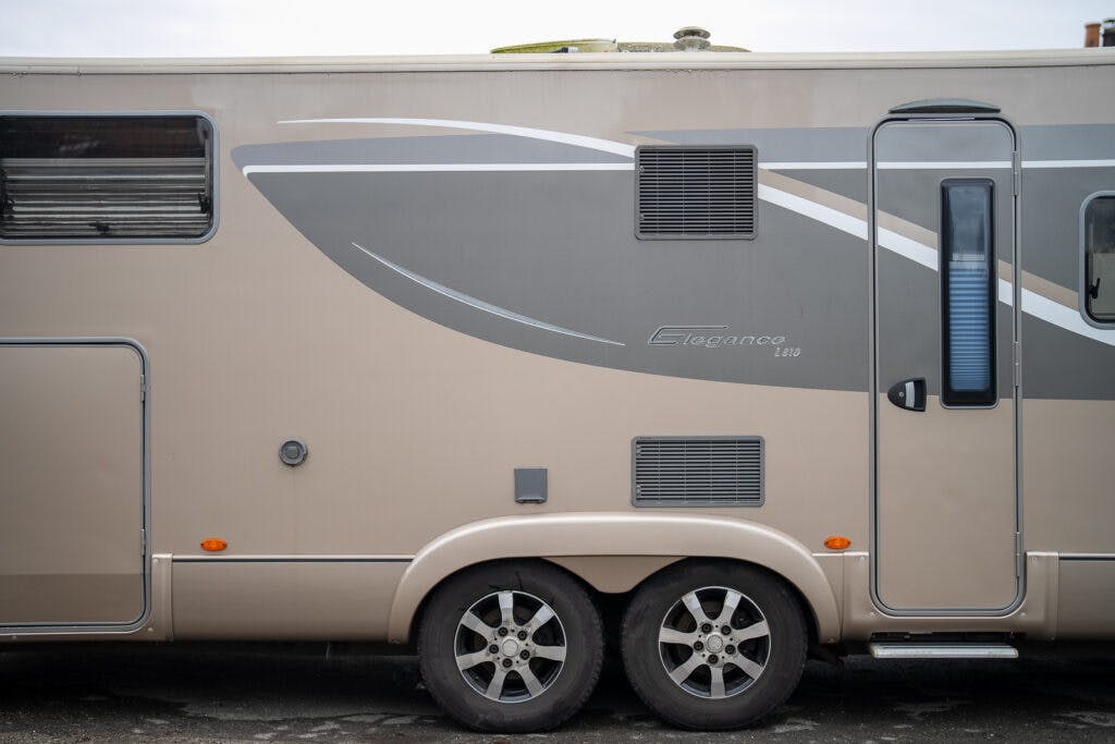 A beige and grey 2013 Burstner Elegance 810 G recreational vehicle with a door and several windows is shown from its side. The vehicle features two large wheels with alloy rims, a small step under the door, and a sleek, modern exterior design.