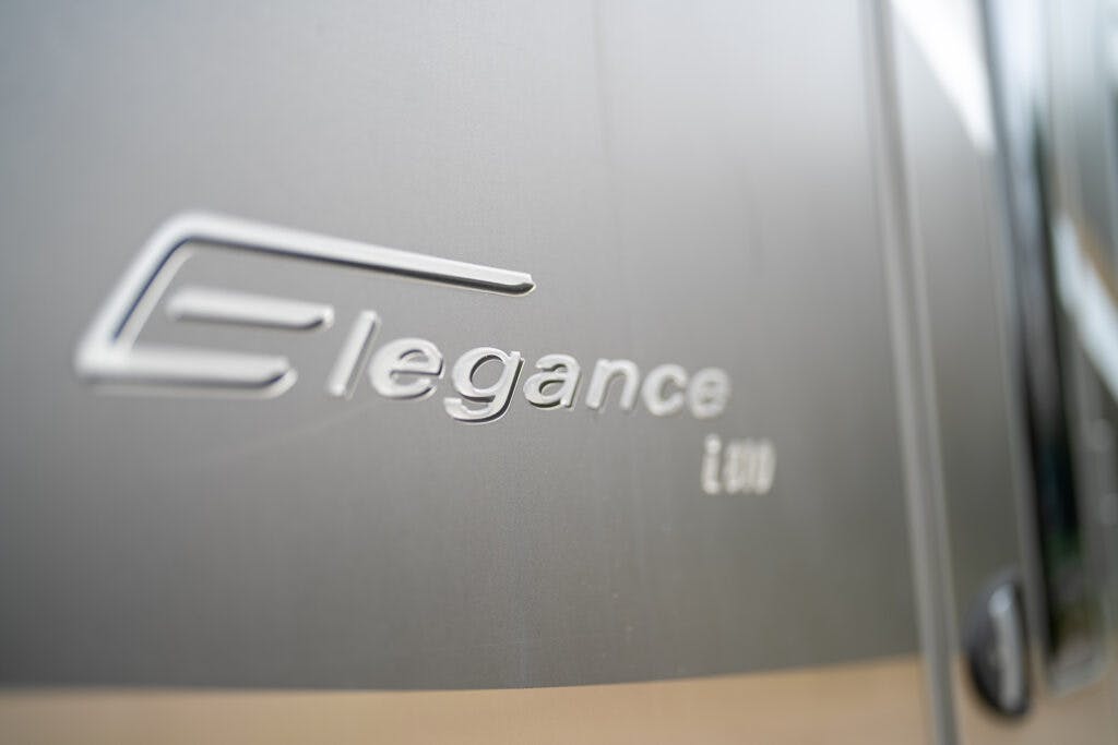 Close-up of a metallic surface showing the embossed text "Elegance i 800". The text is slightly tilted and appears to be part of a vehicle or machinery, specifically resembling the 2013 Burstner Elegance 810 G. The background is out of focus, highlighting the text prominently.