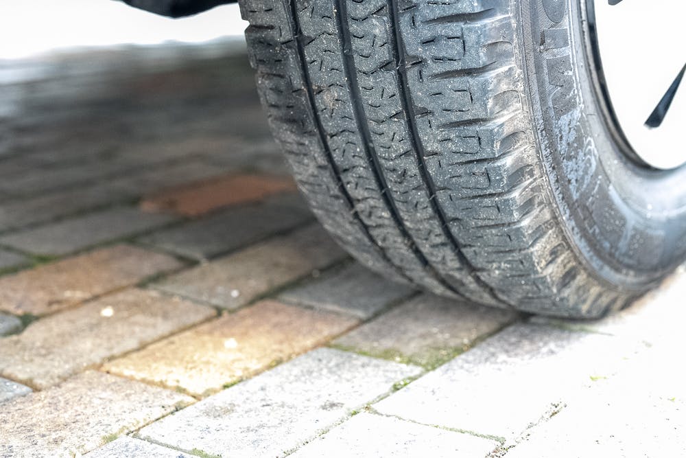 Close-up image of a car tire on a brick-paved surface from the 2016 Roller Team Auto-Roller 707 Low Line. The tire treads are clearly visible, showing some dirt and wear. The bricks beneath the tire are of varying shades of brown and gray.