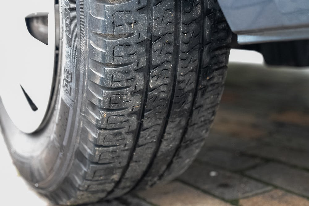 Close-up image of a car tire with clear, detailed tread patterns, mounted on a 2016 Roller Team Auto-Roller 707 Low Line. The pavement beneath it consists of tan and brown rectangular bricks. The lighting suggests it is daytime, with slight shadowing visible.