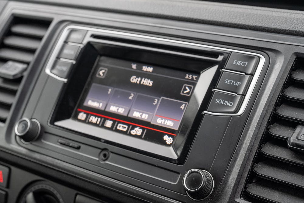 A close-up of a 2019 Volkswagen Transporter T28 Trendline TDI's infotainment system showing a digital display. The screen features a radio interface tuned to "Grt Hits" with station buttons and various control options like eject, setup, and sound on the right side of the display.