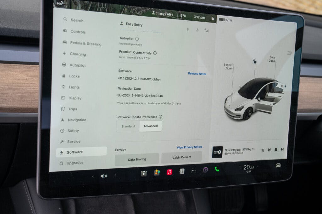 A car dashboard display showing the control panel of a 2021 Tesla Model 3 Long Range AWD. Various settings are displayed, including Autopilot, Navigation, Locks, Lights, Display, and Software updates. A visual of a Tesla car with open doors is also visible on the right side of the screen.