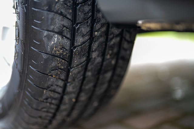 Close-up image of a car tire with visible treads, showing moderate wear and some dirt. The background includes pavement and a slightly blurred area, likely part of the 2019 Benimar Tessoro T486's body and surroundings. The scene is well-lit with natural light.