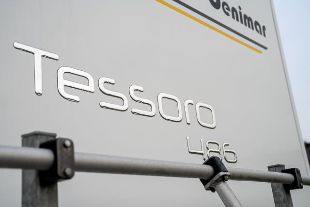 Close-up view of the back of a 2019 Benimar Tessoro T486, showcasing the brand name "Tessoro 486" in metallic lettering. The background is mostly white with part of a logo and some text partially visible in the upper portion of the image.