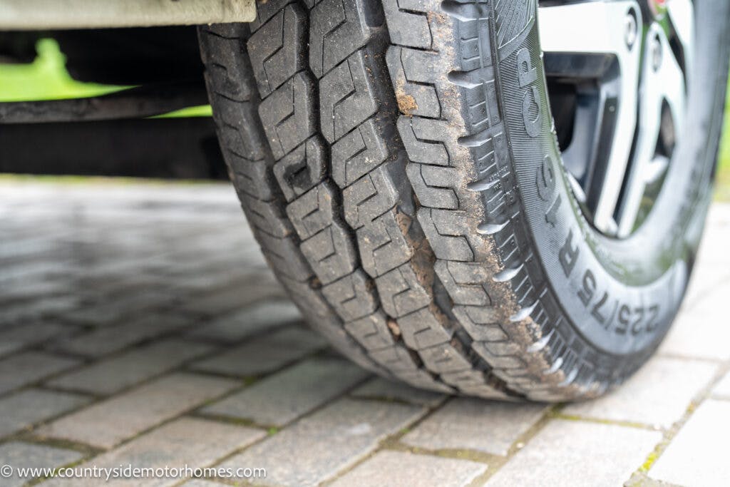 Close-up image of a tire on a 2020 Rapido Dreamer Select Campervan XL, showing the tread pattern clearly. The tire is on a brick-paved surface. The sidewall features the size designation “235/75 R15” and part of a rim is visible in the background.