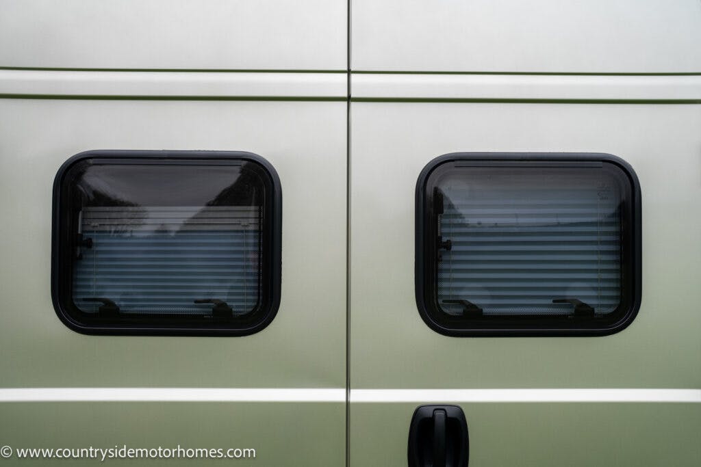 A close-up view of the back of a light-colored 2020 Rapido Dreamer Select Campervan XL with two rectangular windows. The windows have closed blinds, and the website "www.countrysidemotorhomes.com" is visible in the bottom left corner.