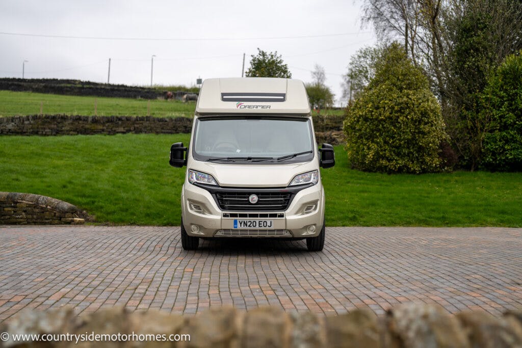 A white 2020 Rapido Dreamer Select Campervan XL is parked on a paved driveway in a rural setting. There is a lawn and trees in the background. The front of the campervan faces the camera, showing its license plate, which reads "YN20 EOJ.
