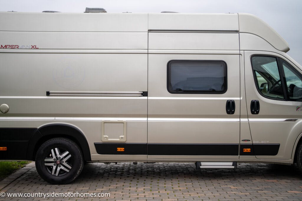 A beige 2020 Rapido Dreamer Select Campervan XL is parked on a paved surface. The vehicle features a side window and black accents along the lower part. Part of the front driver's side mirror and wheel is visible. The URL www.countrysidemotorhomes.com is printed at the bottom left.