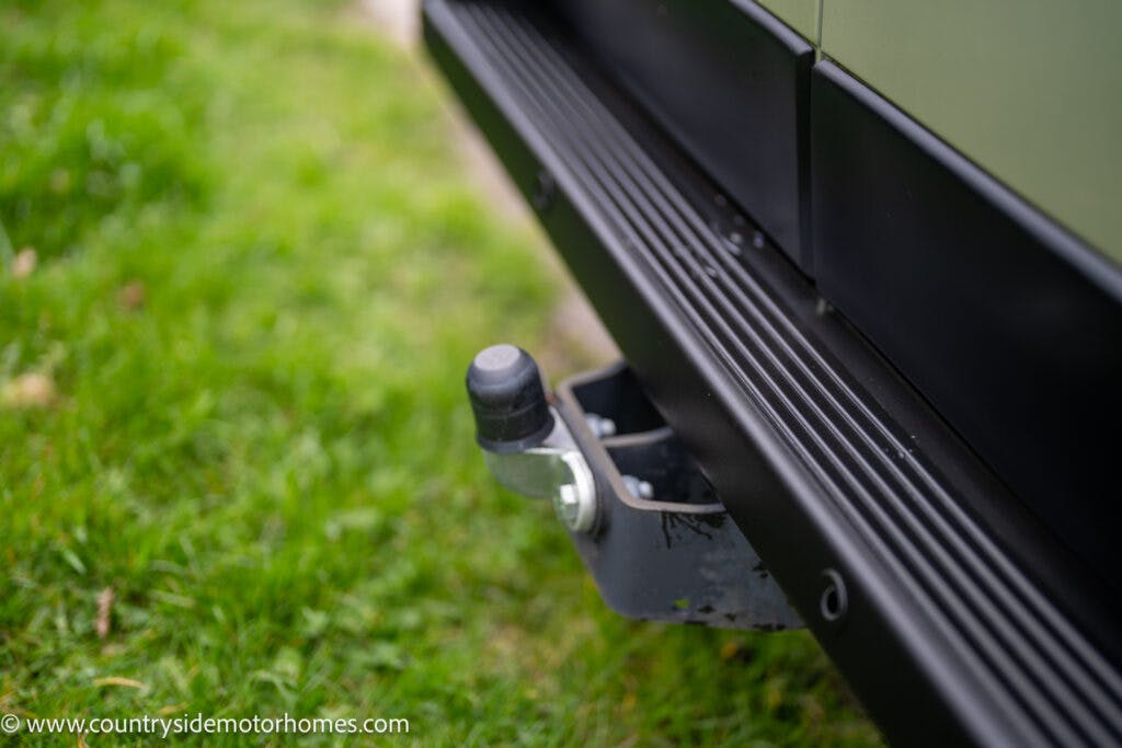 Close-up of a trailer hitch on the back of a 2020 Rapido Dreamer Select Campervan XL, surrounded by green grass. The image shows the hitch receiver and the tow ball shank with a protective cover. The website "www.countrysidemotorhomes.com" is visible in the bottom left corner.
