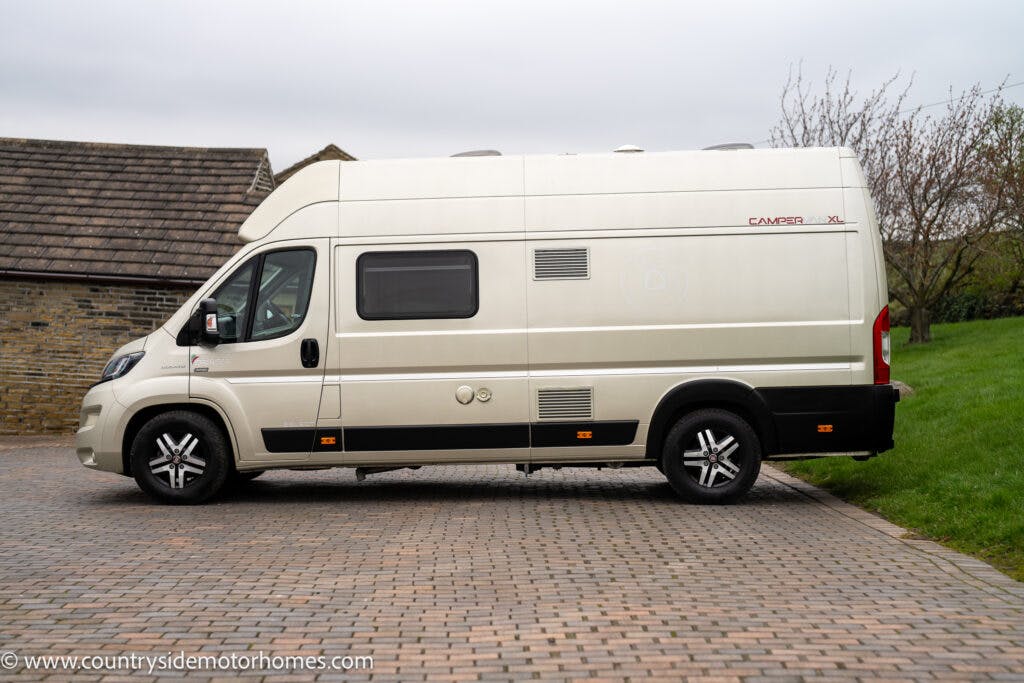 A 2020 Rapido Dreamer Select Campervan XL is parked on a brick driveway next to a rustic stone building. Trees with sparse foliage are visible in the background. The website "www.countrysidemotorhomes.com" is printed at the bottom left of the image.