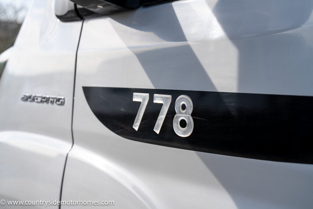 The image shows a close-up of a white vehicle with the number "778" prominently displayed on the side in reflective material. The vehicle branding "SPRINTER" can be seen above the number, near the side mirror. A website address, countryside motorhomes, is visible at the bottom. This 2021 Chausson 778 Premium model offers top-notch features.