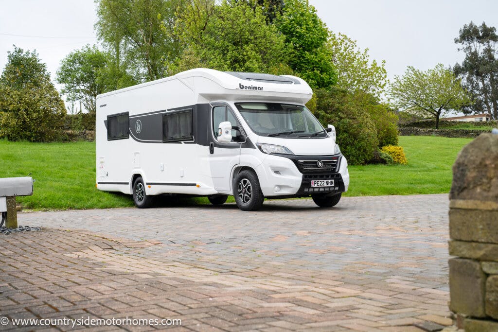 A white 2022 Benimar Mileo 282 motorhome with the logo "Benimar" is parked on a paved driveway surrounded by a grassy area and trees. The license plate reads "PE22 WMN." In the lower left corner, the text "www.countrysidemotorhomes.com" is visible.