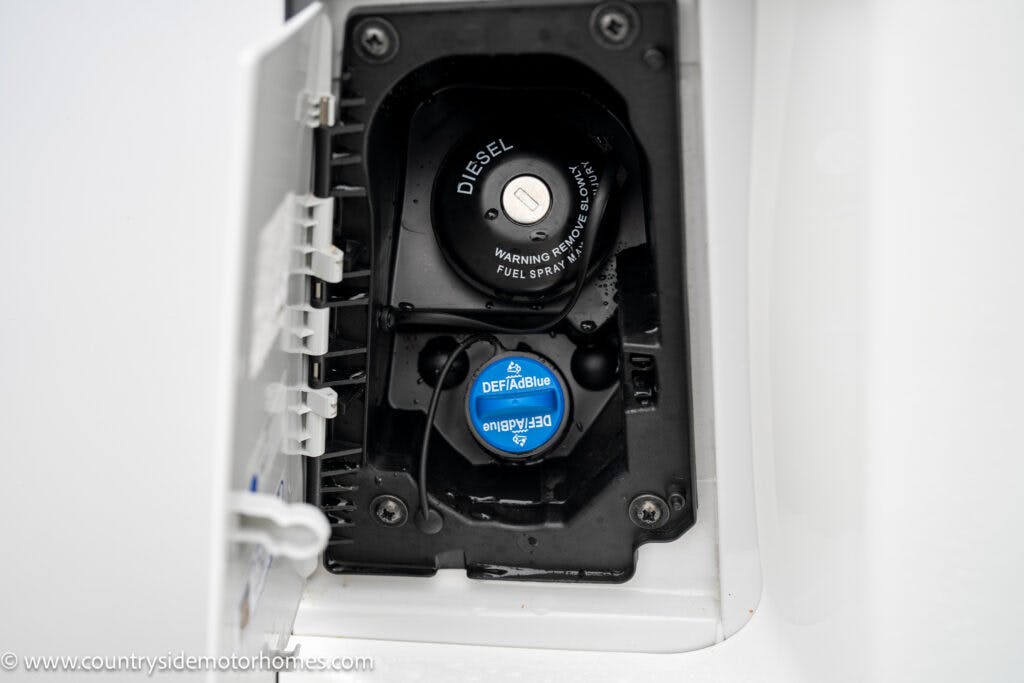The image shows the open fuel filler compartment of a 2022 Benimar Mileo 282. It features a black fuel cap labeled "DIESEL" and a blue cap labeled "DEF/AUS 32" for diesel exhaust fluid. The surrounding area is white, with a website address noted on the lower left corner.