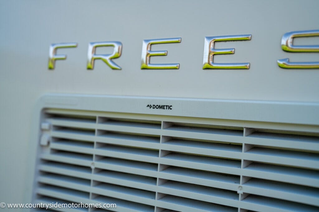 Close-up of vent detail on a 2019 Swift Escape 694 Freestyle motorhome. Shows Dometic logo on the vent, which is below large, spaced letters spelling "FREES" on the vehicle's exterior. Website "www.countrysidemotorhomes.com" visible in the bottom left corner.