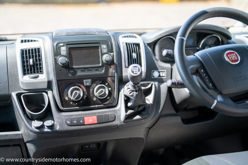 The image shows the dashboard of a 2019 Swift Escape 694 Freestyle motorhome. Visible are a steering wheel with the Fiat logo, a gear shift, various control knobs, air vents, and an infotainment system. The URL "www.countrysidemotorhomes.com" is displayed at the bottom left corner.