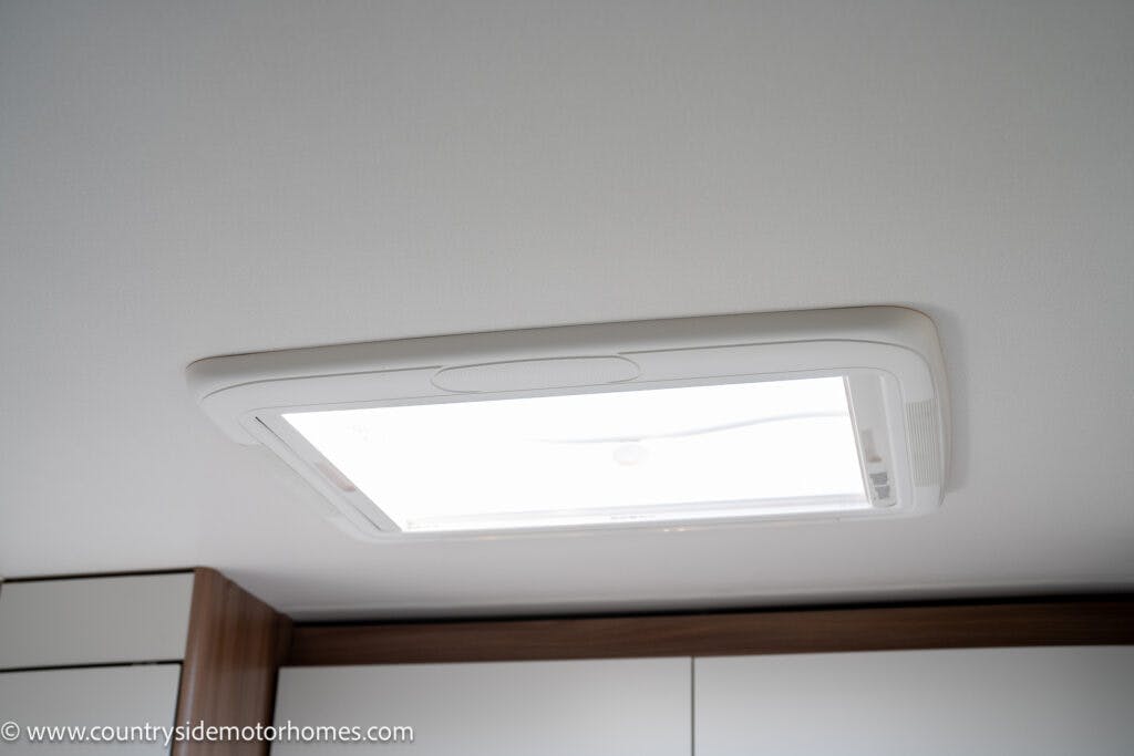 A ceiling-mounted skylight in the 2019 Swift Escape 694 Freestyle motor home, with a white frame and translucent panel, allowing natural light into the interior. The website URL is visible at the bottom left corner.